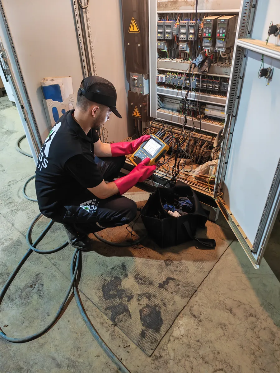 A Class Enerji mühendisi elektrik panosunda yalıtımlı eldivenlerle Class A güç analizörü bağlantısı yapıyor